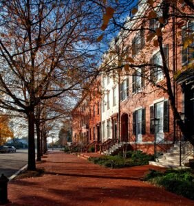 Elegant row houses line a tree-shaded street in Washington DC during autumn.